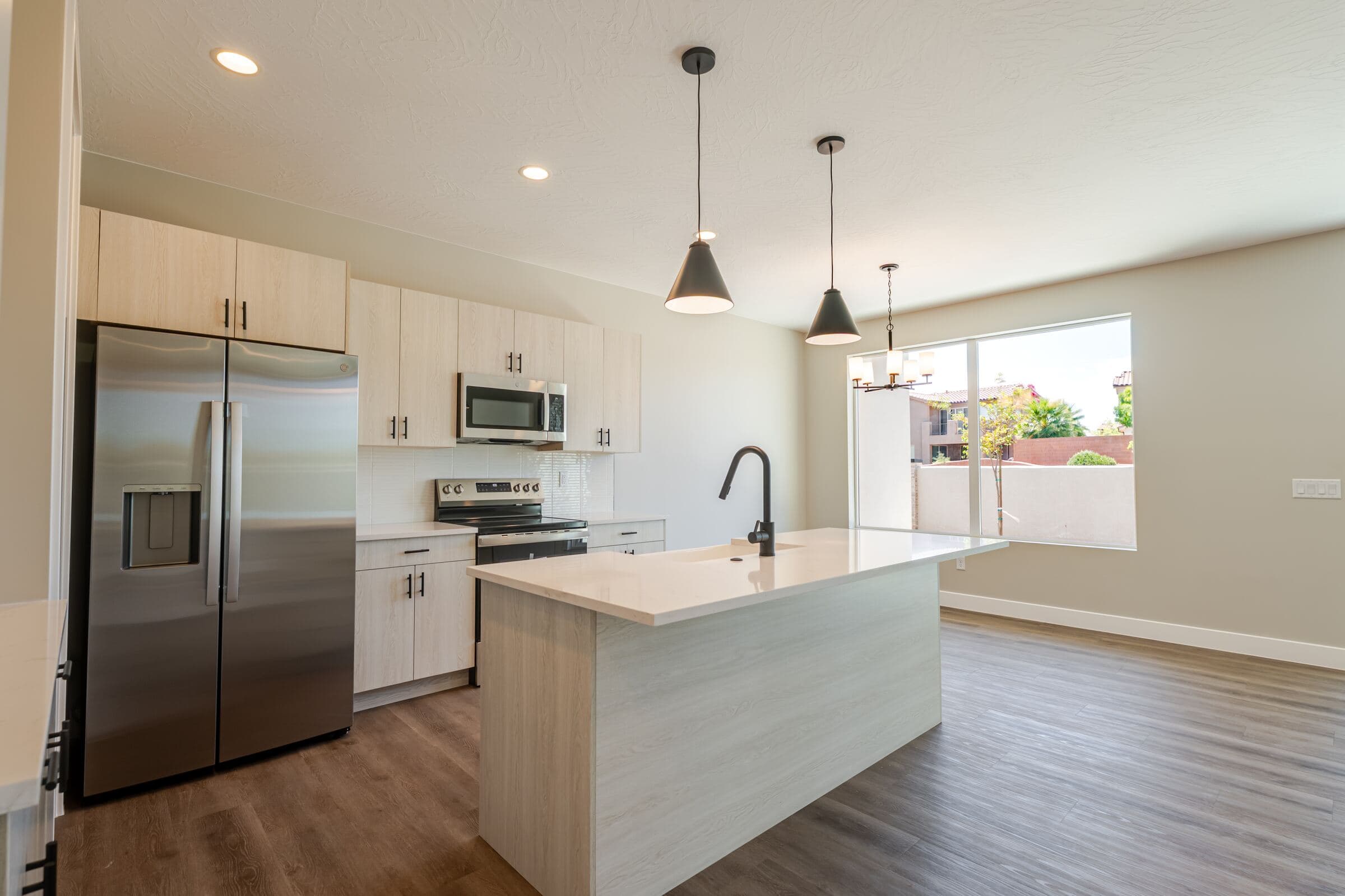 Kitchen with quartz island, pendant lighting, and stainless steel appliances